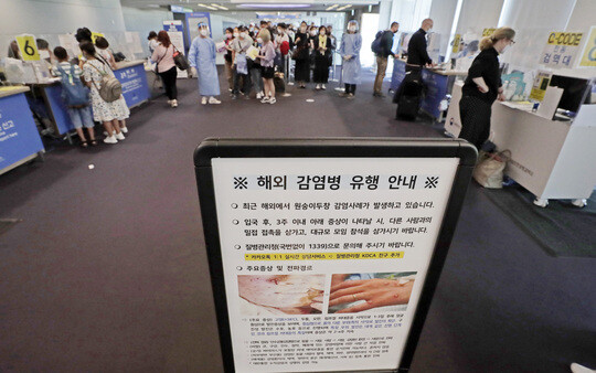 지난 달 27일 오전 인천국제공항 제1터미널 입국장에 해외입국자들이 검역을 받기 위해 대기하고 있다. 승객들 앞에는 원숭이두창 관련 안내문이 세워져 있다. 사진=연합뉴스