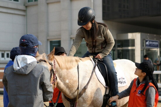 재활승마 강습생이 말을 쓰다듬으며 말과 교감하고 있다. 사진=한국마사회 부산경남본부 제공