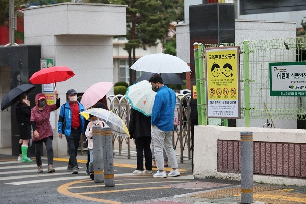 비오는 날 학교 앞에서 우산을 들고 자녀를 기다리는 학부모. 사진=남경원 기자