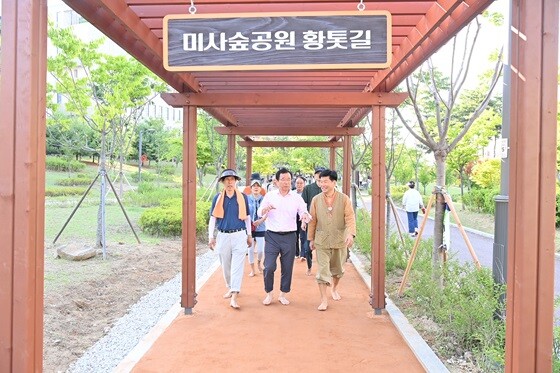 이현재 시장이 개장식 참가자들과 함께 미사숲공원 황톳길을 맨발로 걷고 있다. 사진=하남시 제공