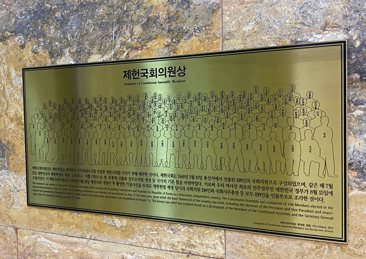 국회 본관 중앙홀에 있는 제헌국회의원상 설명 안내문에는 1948년 5월 31일 제헌국회 개원식 후 촬영한 기념사진을 토대로 조각했다는 내용이 적혀 있다. 사진=정소영 기자