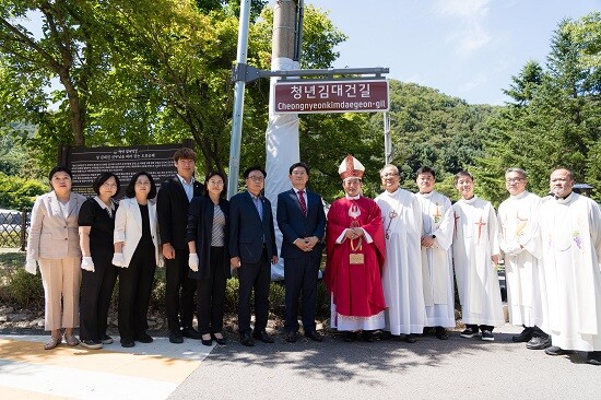 용인시의회 의원연구단체 '용인, 역사종교문화 여행의 시작2' 소속 의원들이 11일 '청년 김대건 길' 명예도로 현판 아래에서 이상일 용인시장, 문희종 주교, 수원교구 소속 신부님 등 사제들과 기념 촬영을 하고 있다. 사진=용인시의회 제공