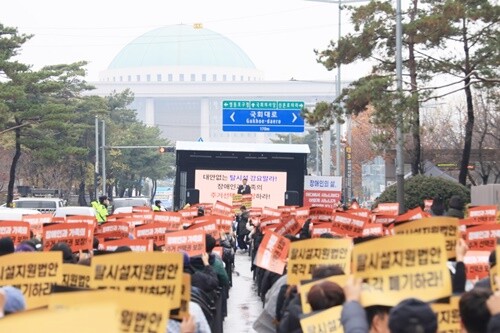 집회 참석자들이 국회를 향해 ‘현실적 논의’와 ‘다양한 주거 선택권 보장’을 촉구하고 있다. ‘대안 없는 탈시설 반대’ 구호가 현장을 가득 메웠다. 사진=김현술 기자