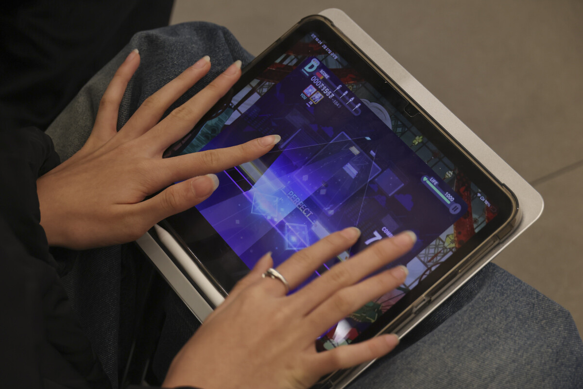 입장을 기다리는 시민이 모바일 리듬게임을 즐기고 있다.