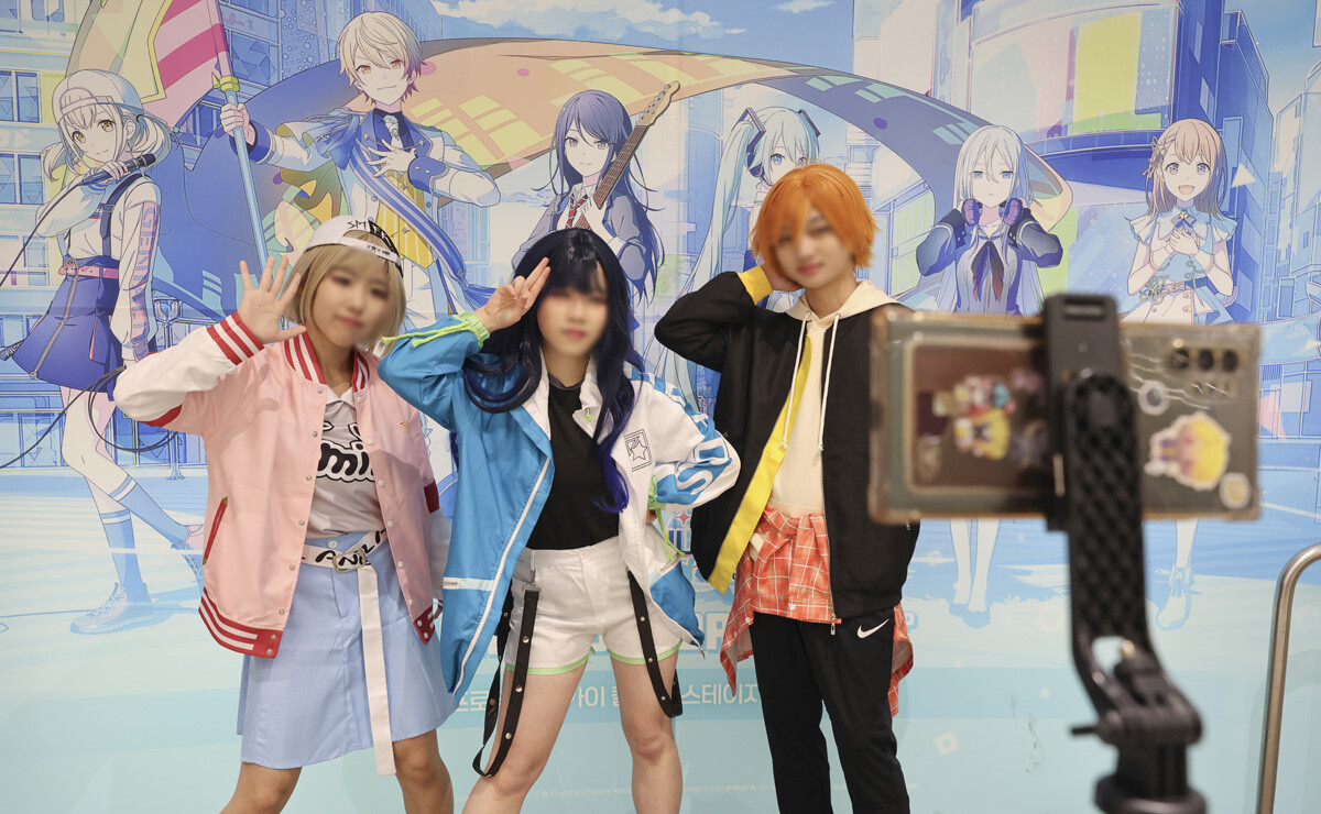 '프로젝트 세카이' 캐릭터 코스튬 복장을 한 청소년들이 휴대폰으로 릴스를 찍고 있다.