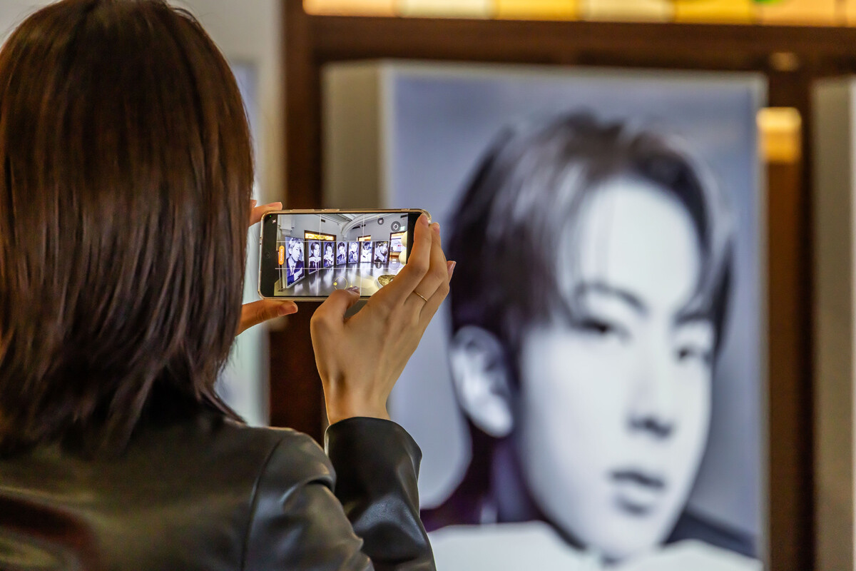 한 팬이 BTS 정규 5집 발매 기념 팝업스토어에서 멤버들의 사진을 휴대폰에 담고 있다. 사진=최준필 기자