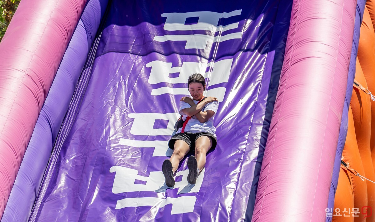 한 시민이 반포한강공원에 설치된 대형 에어바운스 미끄럼틀을 타며 환하게 웃고 있다.