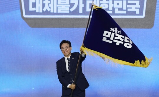 8월 17일 대전 컨벤션센터에서 열린 더불어민주당 8·17 전당대회에서 차기 당대표로 선출된 김민석 대표가 당기를 넘겨받아 흔들고 있다. 사진=이종현 기자